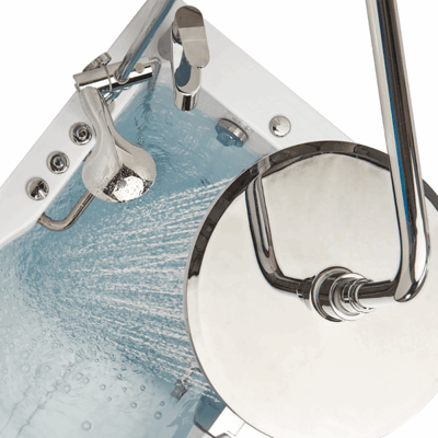 Gros plan d’un kit de colonne de douche à effet pluie chromé et d’un robinet monté sur le rebord remplissant une baignoire à porte Ella d’eau bleue bouillonnante