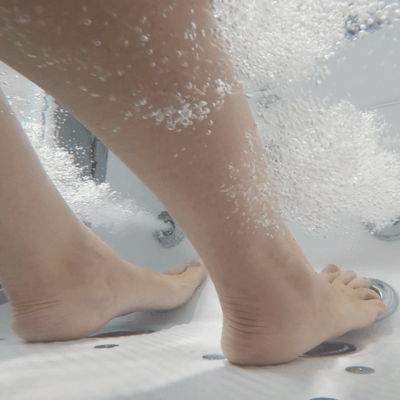 Close-up of bare feet standing on anti-slip floor jets inside an Ella walk-in tub with bubbling water massage