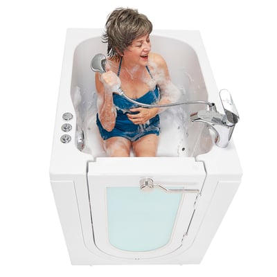 Femme âgée riant en utilisant une douchette à main à l’intérieur de la baignoire à porte Ella’s Bubbles AllFit à entrée frontale