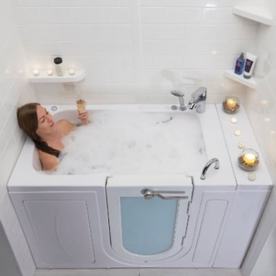 Woman relaxing with a glass of champagne in a bubble-filled Ella Capri acrylic walk-in bathtub with outward swing door