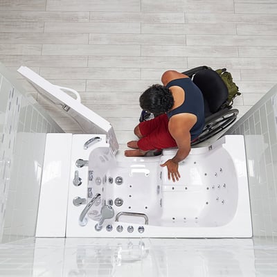 Person transferring sideways from chair into the Ella Transfer30 walk-in tub with open door and jet massage system