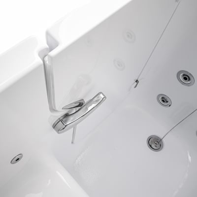 Chrome latch handle on the open door of a walk in tub, with the chain stopper drain and textured floor behind it.