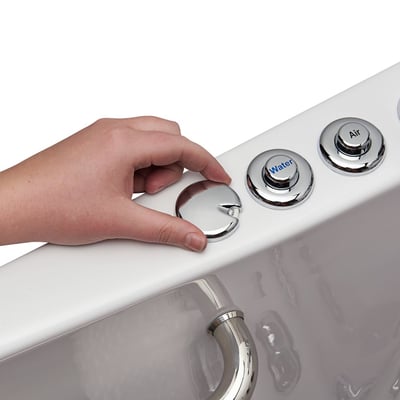 Gros plan d’une main tournant une molette de commande chromée sur une baignoire à porte Ella, avec les boutons des jets Eau et Air visibles sur le rebord