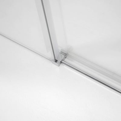 Primer plano del carril inferior cromado y los herrajes de bisagra en un panel de puerta de ducha corredera de vidrio templado de 6 mm