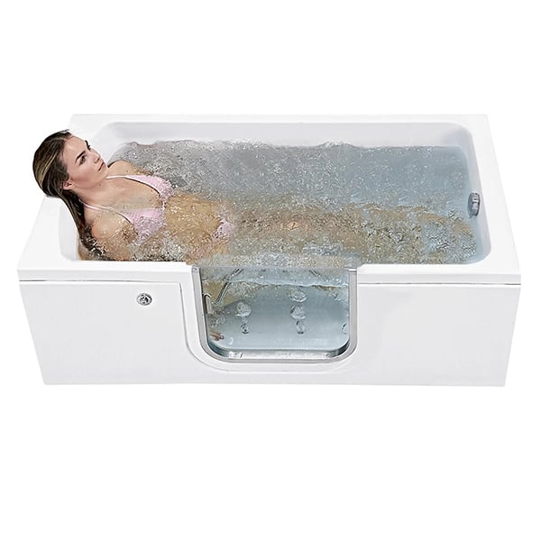 Woman reclining and enjoying an air bubble massage in an Ella lay-down walk-in tub with glass door panel