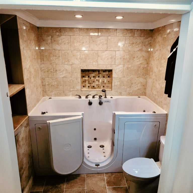 Ella walk-in tub with open door installed in a tiled bathroom with mosaic niche, recessed lighting, and adjacent toilet