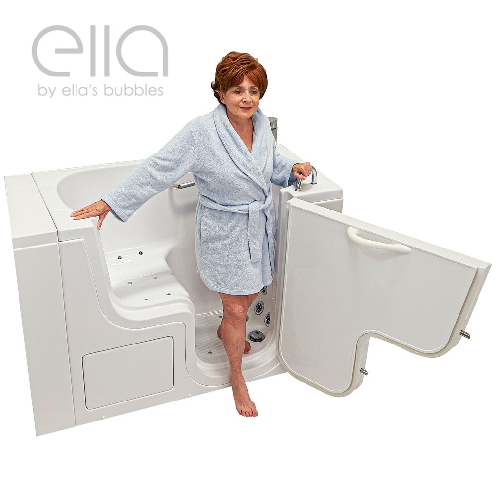 Senior woman in a blue robe stepping into the Ella Transfer26 walk-in tub with open outswing door and grab bars