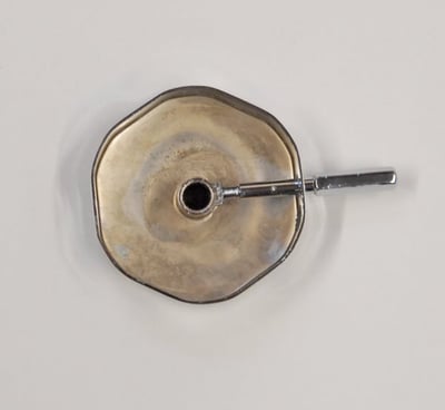 Close-up of a walk-in tub drain opener kit with a brass disc and chrome extension screw handle tool