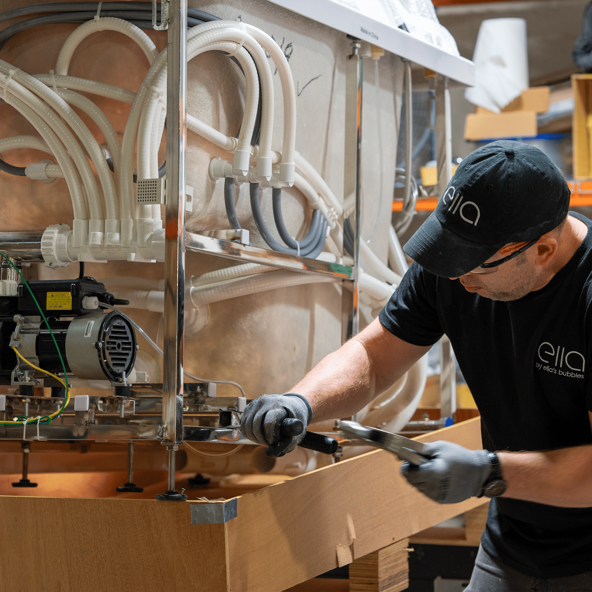 Ella's Bubbles technician assembling the pump and air lines on a walk-in tub frame in the Chicago workshop