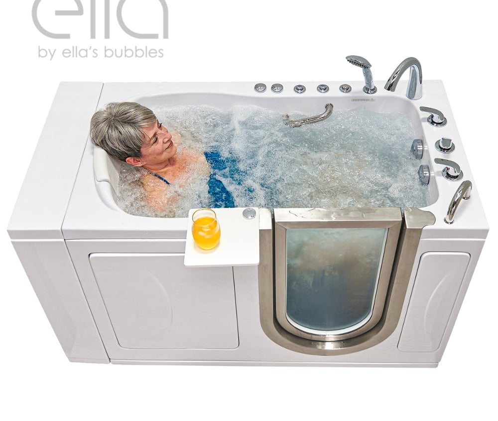 Senior woman relaxing in an Ella walk-in tub with hydro massage jets and a swivel tray holding an orange juice drink