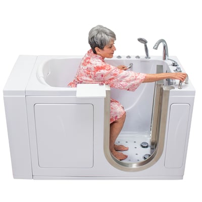 Senior woman in floral top seated inside an Ella Elite walk-in tub adjusting controls with anti-slip floor and chrome faucet fixtures
