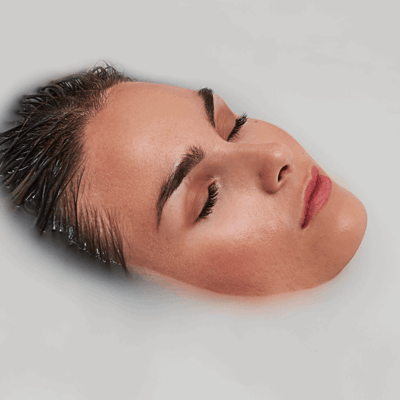 Personne se relaxant les yeux fermés et les cheveux mouillés immergés dans le bain de massage à air de la baignoire à porte Ella Laydown
