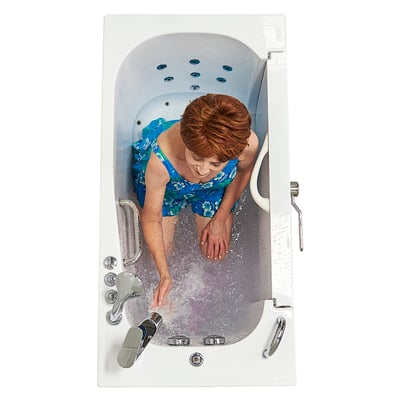 Overhead view of a senior woman in a floral swimsuit running her hands through hydro massage jets in an Ella walk-in tub