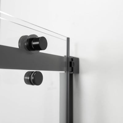 Primer plano de los herrajes de la puerta corredera en negro mate y el panel de vidrio templado en una cabina de ducha accesible Ella Primo