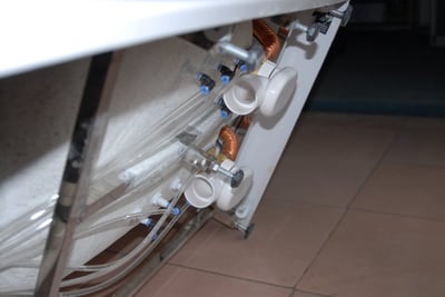 Close-up of internal plumbing tubing and drain elbow components beneath an older discontinued Ella walk-in tub model