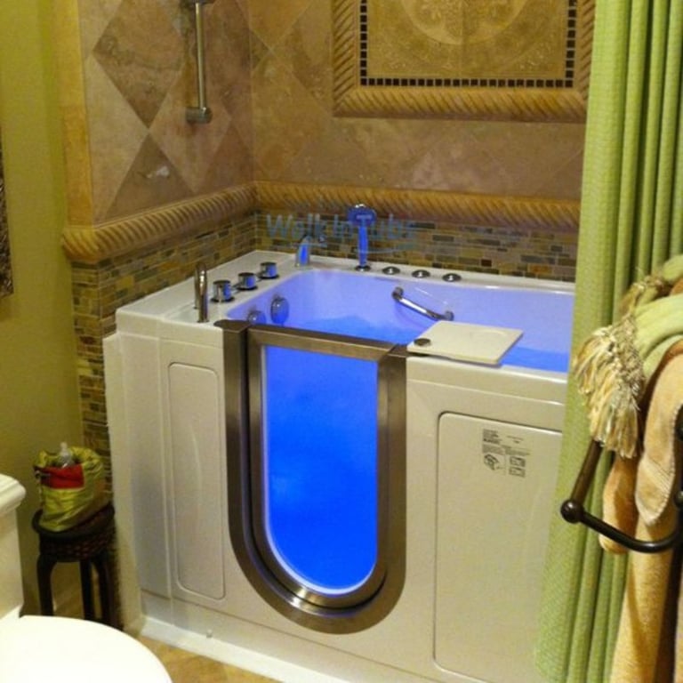 Ella walk-in tub with glowing blue chromotherapy lighting installed in tiled bathroom with stainless steel door