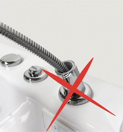 Red X over walk-in tub chrome faucet fixture showing incorrect handheld shower hose installation placement