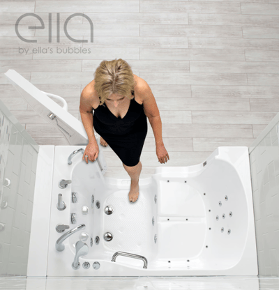 Femme entrant dans une baignoire à porte Ella par la porte ouverte, vue aérienne montrant les jets, les barres d’appui et le sol antidérapant