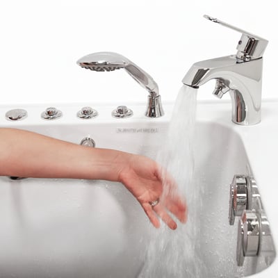 Main testant le débit d’eau chaude du robinet à remplissage rapide à levier unique Ella’s Bubbles sur une baignoire à porte avec boutons de commande