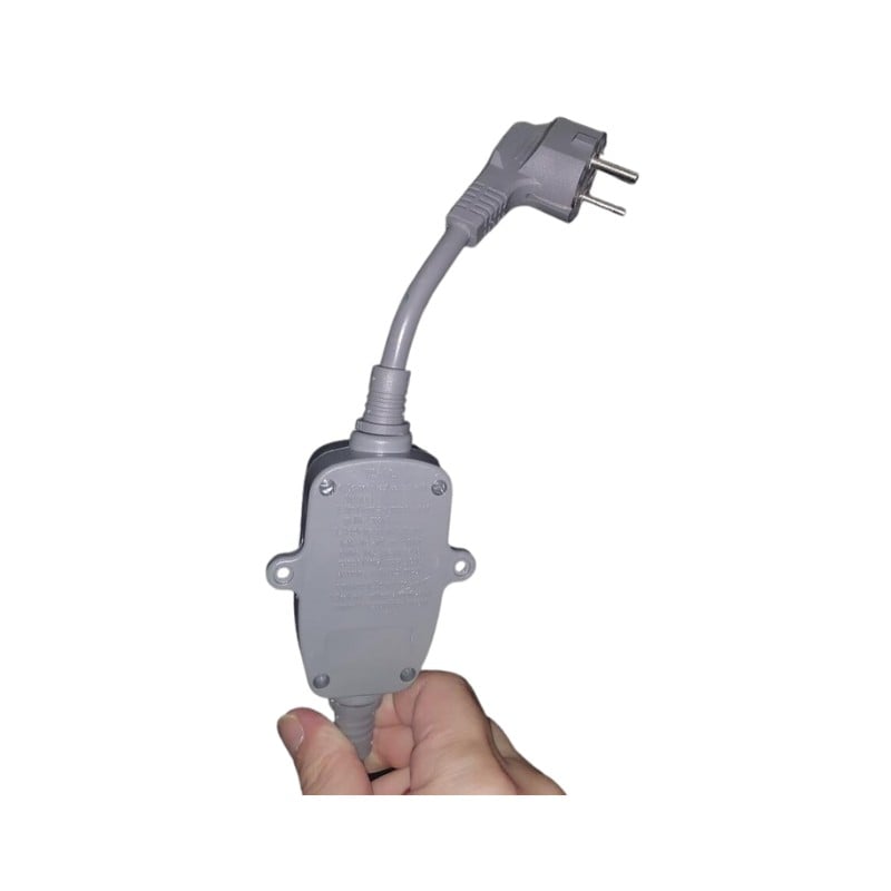 Mano sosteniendo un enchufe gris impermeable de protección contra fugas GFCI y una caja de conexiones para bañera con puerta