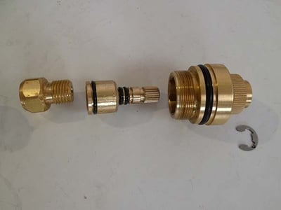 Disassembled brass thermostatic control valve cartridge components with O-rings and retaining clip for walk-in tub