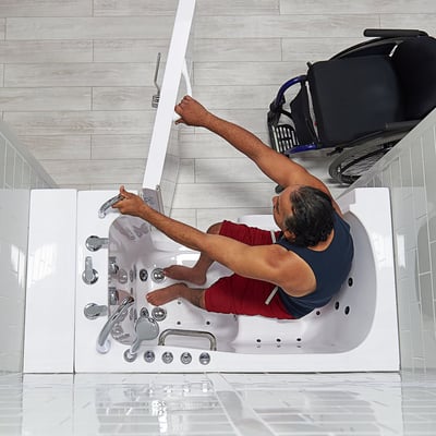 Person transferring independently into the Ella Transfer30 walk-in tub with door open and mobility aid parked alongside