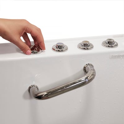 Close-up of a hand pressing chrome push-button controls on an Ella walk-in tub with a stainless steel grab bar below