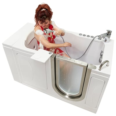 Woman using a handheld showerhead while seated inside an Ella walk-in tub with open stainless steel door and hydro jets
