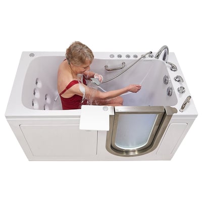 Senior woman in red swimsuit using handheld showerhead while seated in Ella Ultimate walk-in tub with hydro massage jets and outward swing door