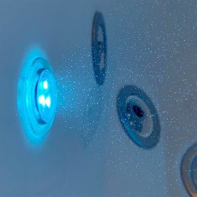 Gros plan d’un éclairage LED bleu et de jets d’eau sur la paroi intérieure d’une baignoire à porte Ella Petite