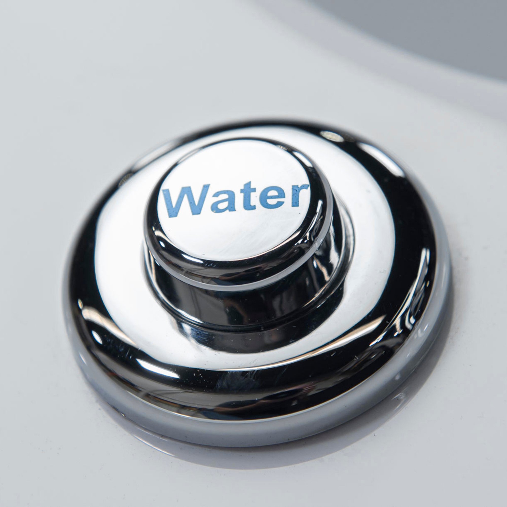 Close-up of the chrome Water push button control on an Ella walk-in tub deck