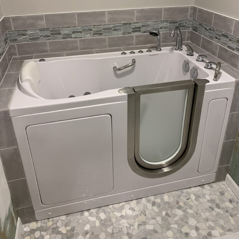 White Ella walk-in tub with outward swing door, hydrotherapy jets, and grab bar installed in tiled bathroom