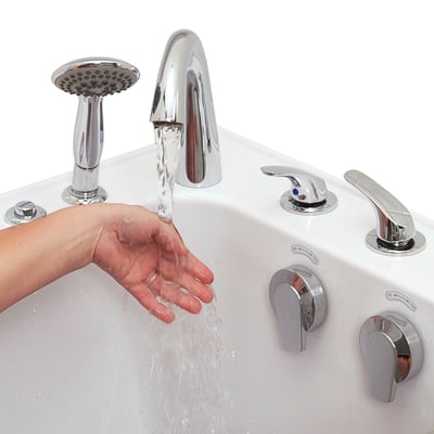 Close-up of a hand testing water temperature from the chrome Roman faucet on an Ella walk-in tub with handheld showerhead and jet controls