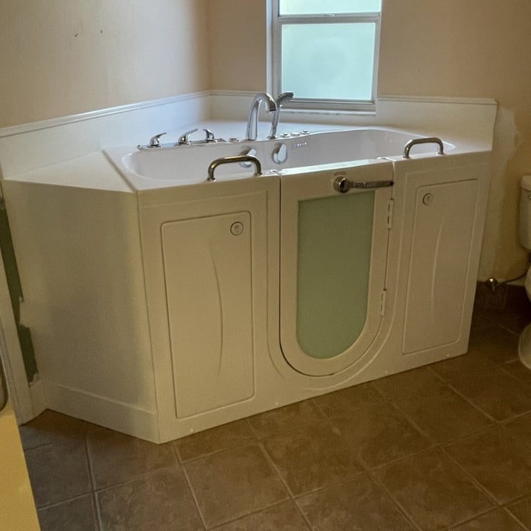 White Ella walk-in tub with frosted glass door, chrome grab bars, and jets installed in a corner bathroom