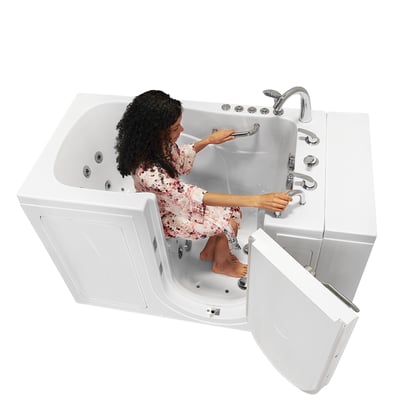Woman in floral robe seated inside Ella Capri walk-in tub gripping grab bars with outswing door open and hydrotherapy jets visible