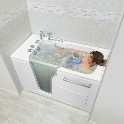 Woman relaxing in an Ella Ultra Acrylic walk-in tub with hydro jets bubbling around her in a white tiled bathroom