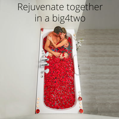 Couple embracing in the Ella Big4Two two-seat walk-in tub filled with red rose petals and candles surrounding