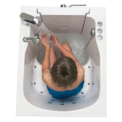 Vue de dessus d’une personne âgée prenant un bain dans une baignoire à porte Ella à entrée frontale, avec l’eau coulant du robinet chromé et les jets d’hydrothérapie visibles