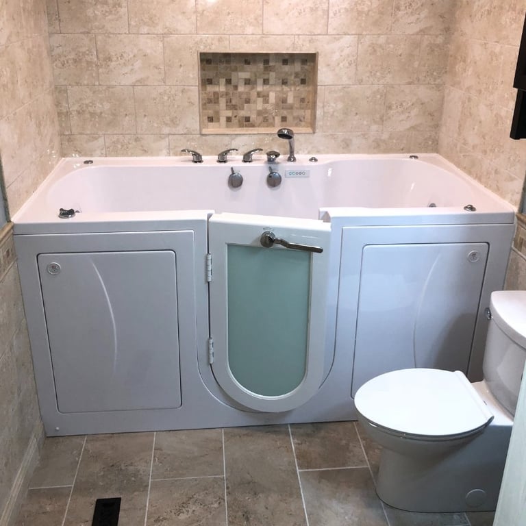 Ella walk-in tub with frosted glass inward swing door installed in a beige tiled bathroom next to a toilet