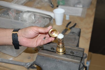 Technician assembling a brass thermostatic control valve cartridge secured in a bench vise during walk-in tub installation