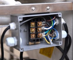 Gros plan d’une boîte de jonction électrique avec des connexions de câblage codées par couleur pour l’installation d’une baignoire à porte