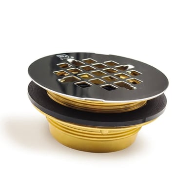 Gros plan de la bonde de douche CSI Bathware DRA1012 avec couvercle à grille chromé et corps en laiton fileté doré sur fond blanc