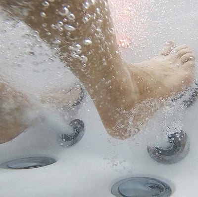 Underwater close-up of feet surrounded by hydrotherapy jets and bubbles inside an Ella Royal walk-in tub