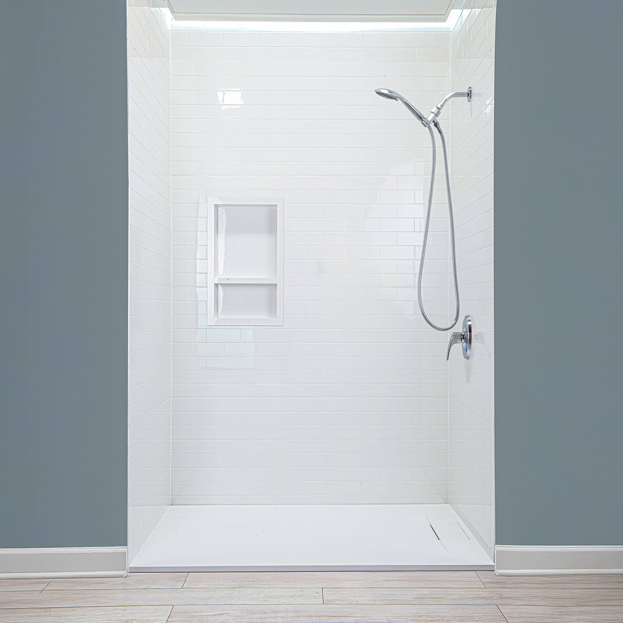 Ella accessible shower stall with white subway tile acrylic wall panels, built-in niche, and chrome handheld showerhead