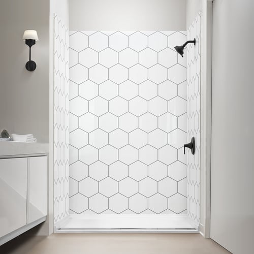 Shower alcove lined with hexagon pattern acrylic shower wall panels above a low threshold white shower base