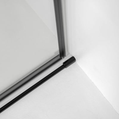 Primer plano del carril de la puerta de ducha corredera de vidrio templado con marco en negro mate y detalle de la esquina del riel inferior