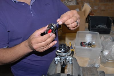 Technician assembling a thermostatic control valve cartridge with pliers at a workshop workbench