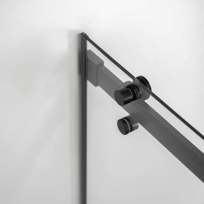 Primer plano de los herrajes y rodillos de la puerta corredera en negro mate en el carril de la puerta de ducha de vidrio templado Ella Primo