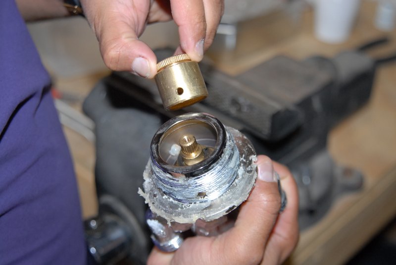 Technician assembling a brass thermostatic control valve cartridge on a workbench