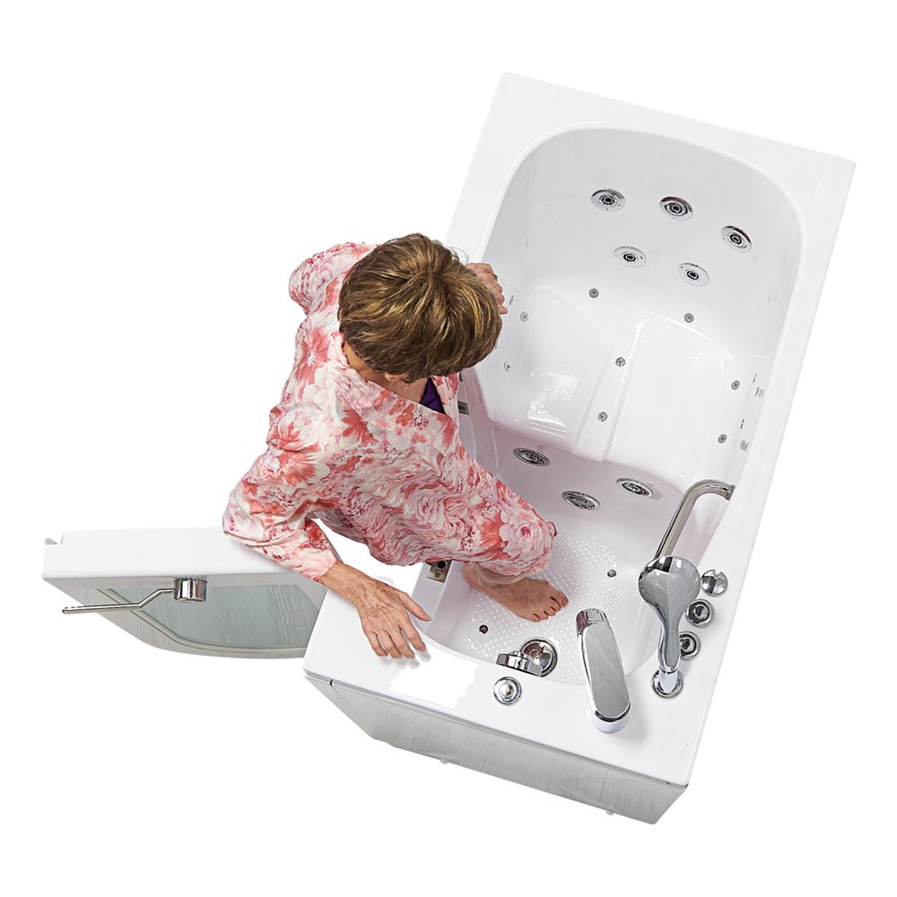 Senior woman stepping into the Ella Mobile walk-in tub over its low threshold through the outward swing door